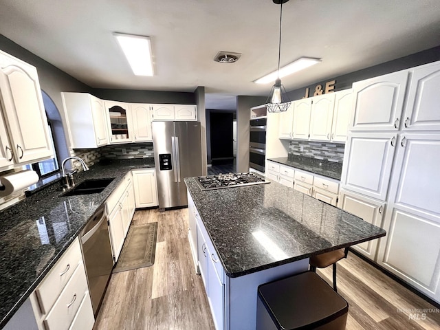 kitchen featuring a center island, sink, appliances with stainless steel finishes, decorative light fixtures, and white cabinetry