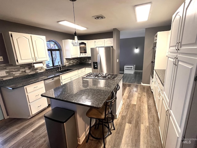 kitchen featuring pendant lighting, white cabinets, sink, appliances with stainless steel finishes, and a kitchen island