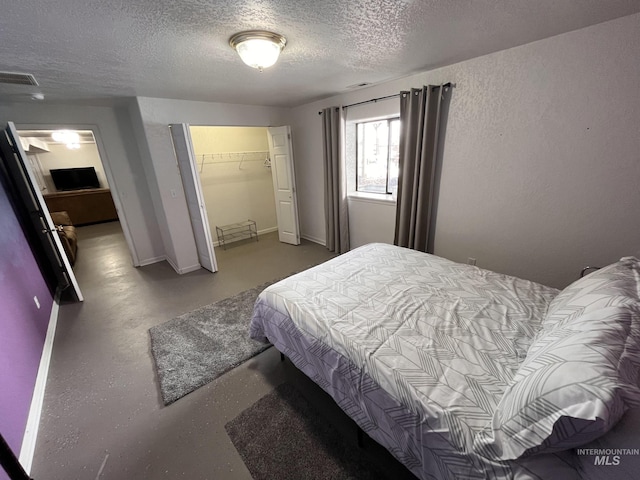 bedroom featuring a spacious closet, a closet, and a textured ceiling