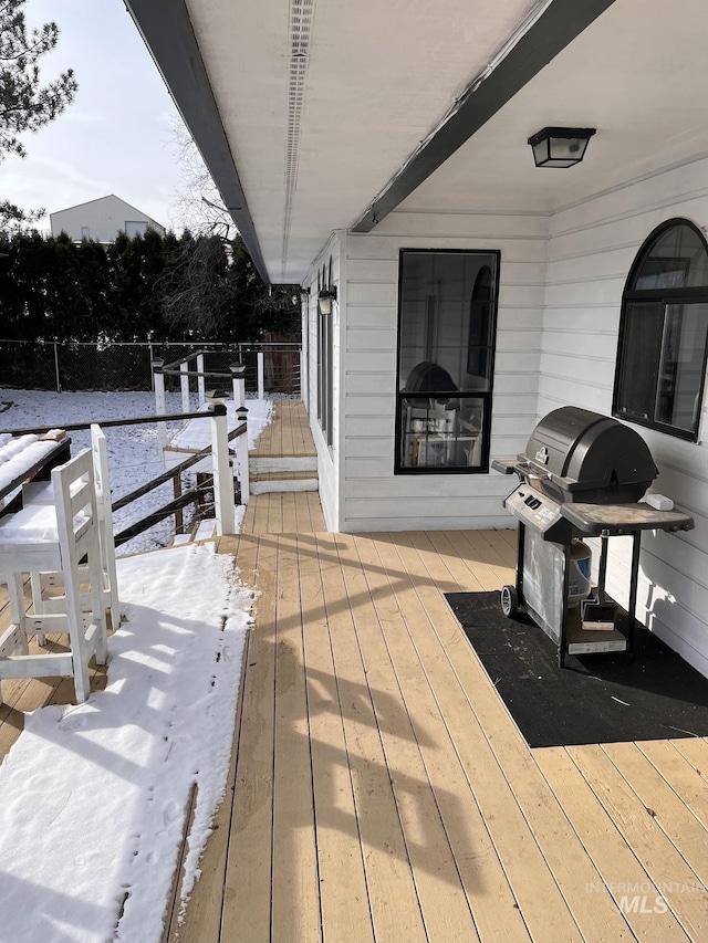 snow covered deck with a grill