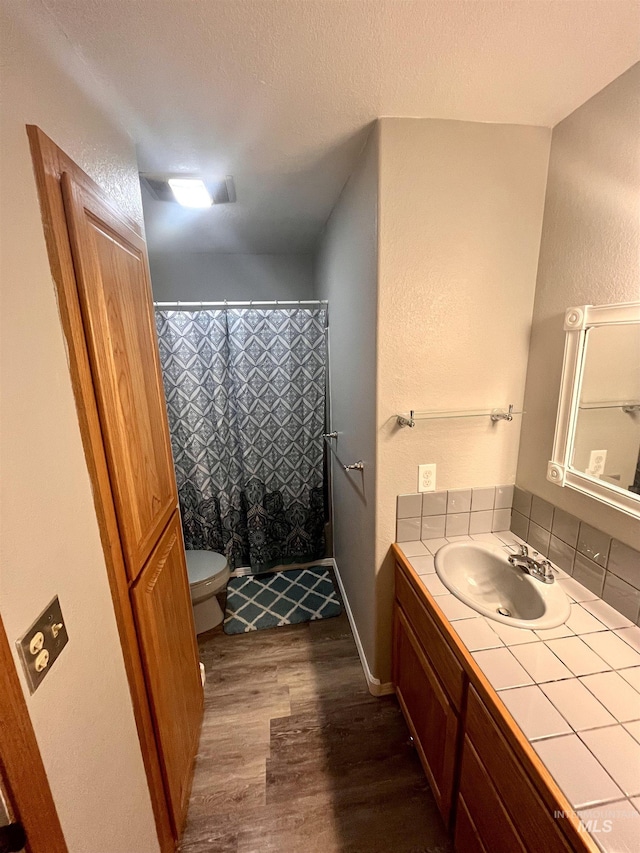 bathroom with curtained shower, wood-type flooring, a textured ceiling, toilet, and vanity