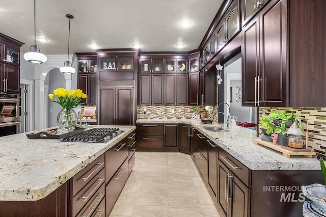 kitchen featuring sink, tasteful backsplash, dark brown cabinets, hanging light fixtures, and stainless steel appliances