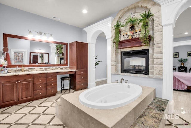 bathroom featuring ornate columns, vanity, and tiled tub