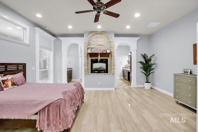 bedroom featuring ensuite bathroom, a fireplace, and light hardwood / wood-style flooring