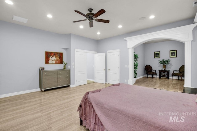 bedroom featuring ceiling fan, light hardwood / wood-style floors, and two closets