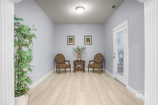 sitting room featuring a textured ceiling and light wood-type flooring