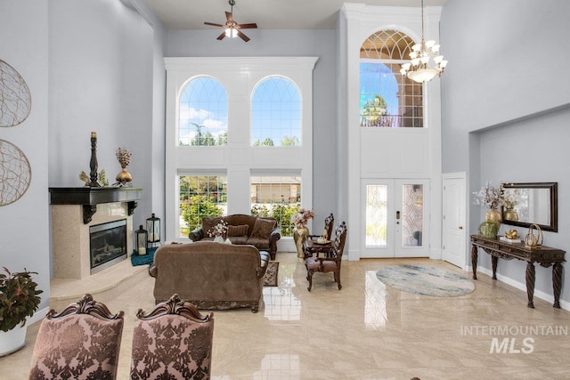 living room featuring a high ceiling, a premium fireplace, an inviting chandelier, and french doors