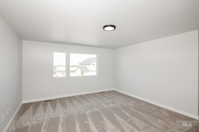 carpeted empty room with visible vents and baseboards