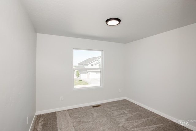 spare room featuring carpet, visible vents, and baseboards