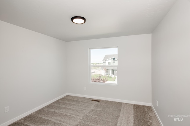 unfurnished room featuring carpet, visible vents, and baseboards