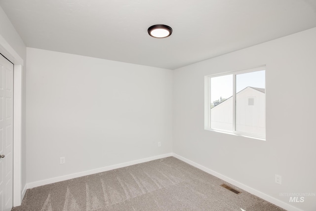 empty room with carpet floors, visible vents, and baseboards