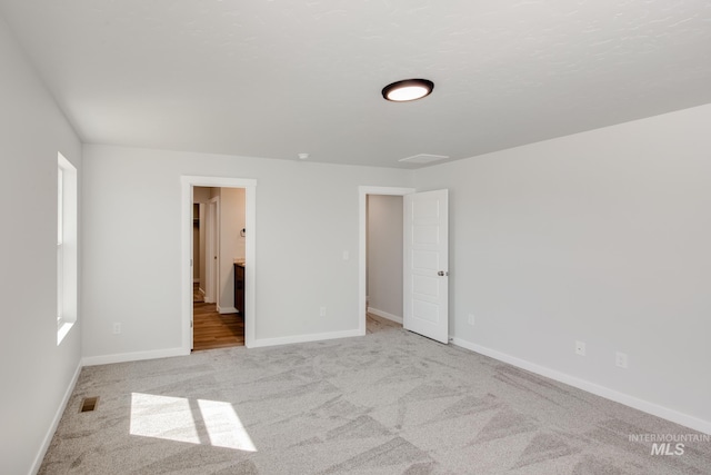 carpeted spare room with visible vents and baseboards