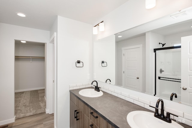 full bath featuring a walk in closet, visible vents, a sink, and a shower stall