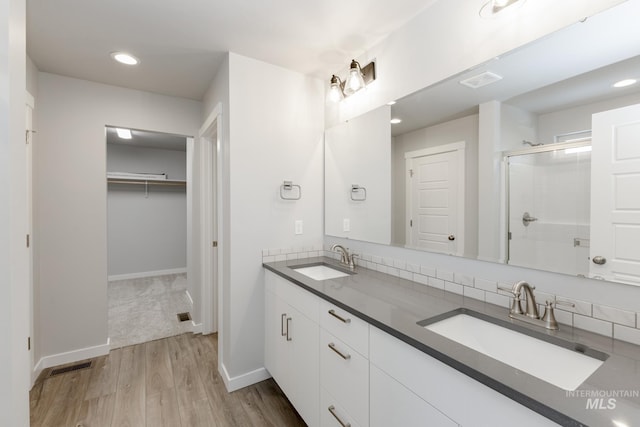 bathroom with wood finished floors, a stall shower, a sink, and visible vents