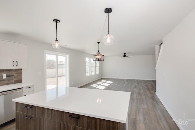 kitchen with white cabinets, dishwasher, a center island, light countertops, and light wood-style floors