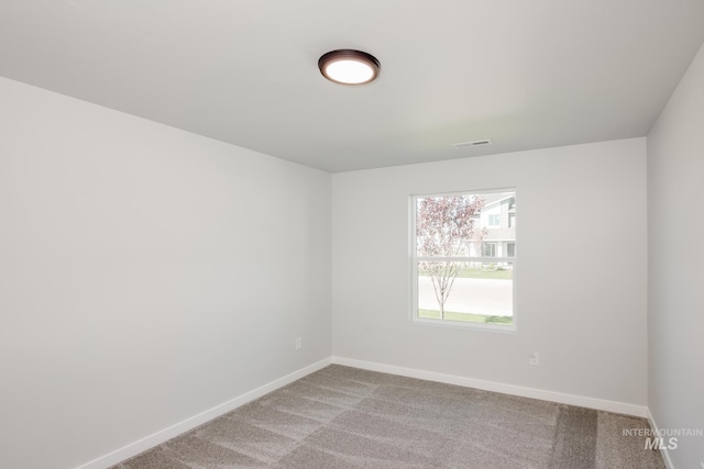 carpeted spare room featuring visible vents and baseboards