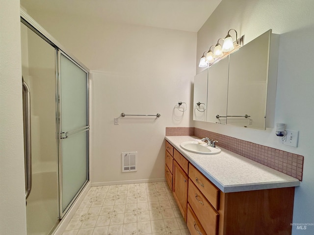 bathroom featuring tasteful backsplash, a shower with shower door, and vanity