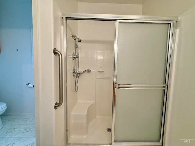 bathroom with a shower with door and toilet