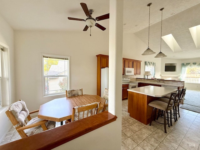 kitchen with ceiling fan, pendant lighting, kitchen peninsula, white appliances, and high vaulted ceiling