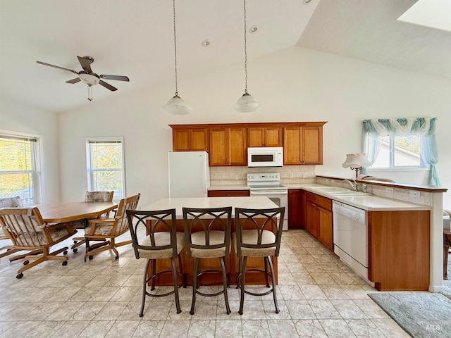 kitchen featuring white appliances, decorative light fixtures, sink, and a healthy amount of sunlight