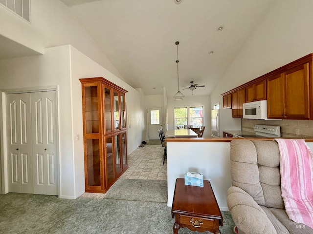 kitchen featuring ceiling fan, kitchen peninsula, tasteful backsplash, white appliances, and light carpet