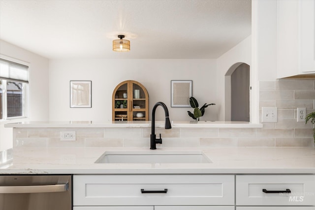 kitchen with a sink, tasteful backsplash, dishwasher, and white cabinetry