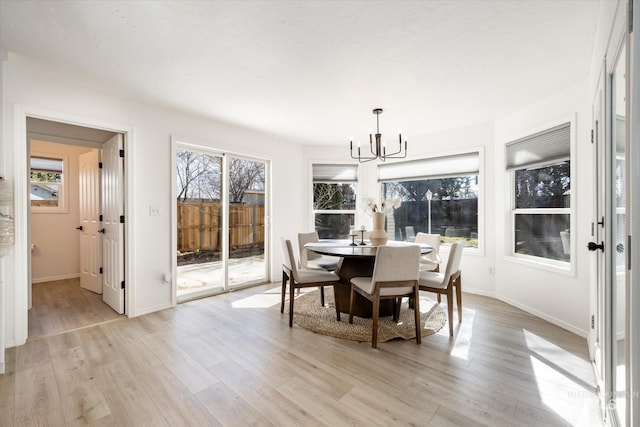 dining area featuring a healthy amount of sunlight, light wood-style floors, and a chandelier