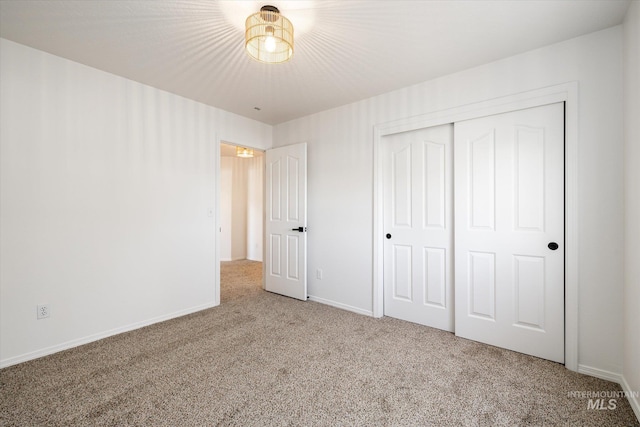 unfurnished bedroom with a closet, baseboards, and carpet flooring