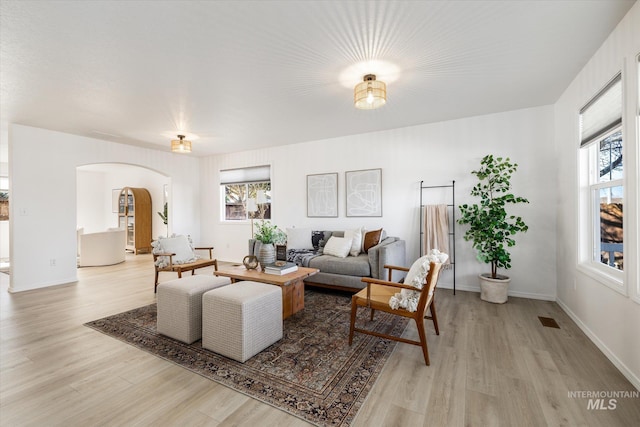 living room featuring visible vents, wood finished floors, arched walkways, and a wealth of natural light