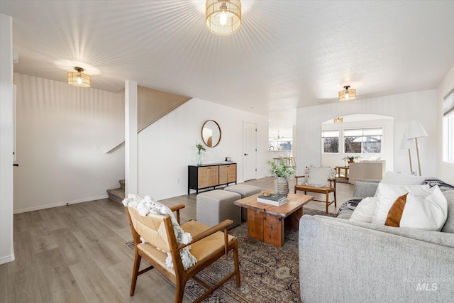 living room with baseboards, stairs, and light wood-style floors