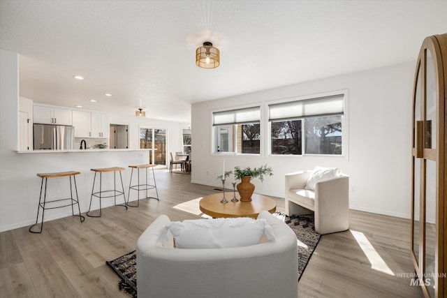 living area featuring recessed lighting, baseboards, and light wood finished floors