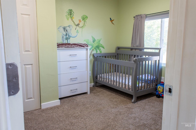 carpeted bedroom featuring a crib and baseboards