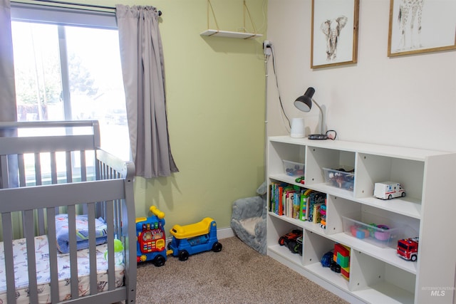 bedroom featuring baseboards, a crib, and carpet