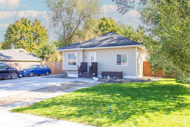 view of front facade featuring driveway, a front yard, and fence