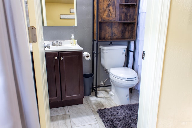 bathroom featuring vanity, toilet, and a textured wall