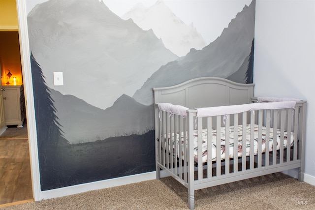 carpeted bedroom with a crib and baseboards