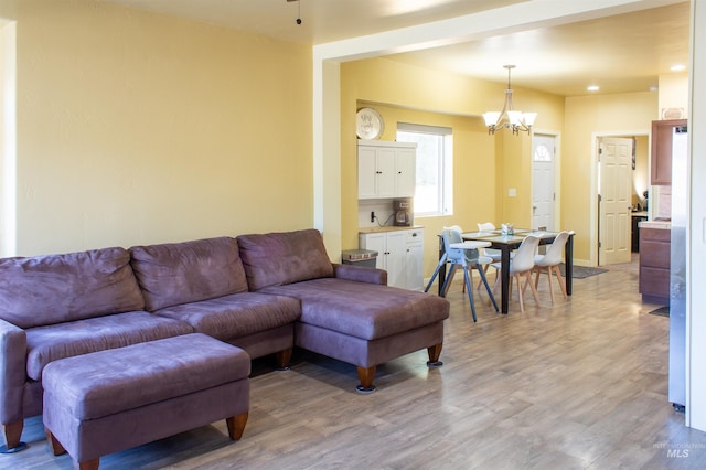 living area with light wood finished floors, baseboards, and an inviting chandelier