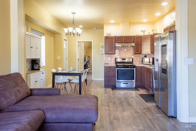 kitchen featuring wood finished floors, stainless steel appliances, light countertops, open floor plan, and tasteful backsplash