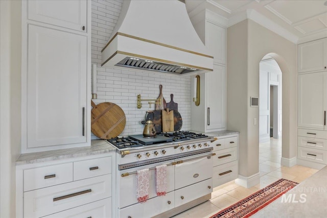 1122 W Two Rivers Ln, Eagle, ID 83616 - kitchen with custom range hood, range with two ovens, tasteful backsplash, white cabinetry, and arched walkways
