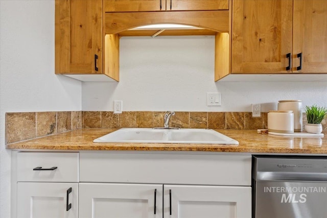 kitchen with a sink, arched walkways, stainless steel dishwasher, and light stone counters