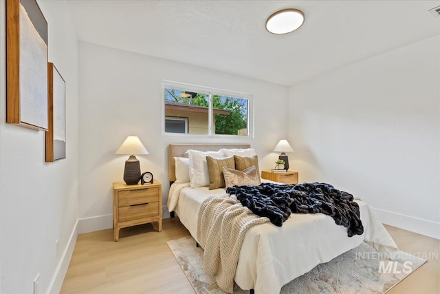 bedroom with baseboards, visible vents, and light wood-style floors