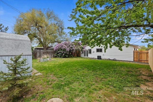 view of yard with a fenced backyard, central AC, and french doors