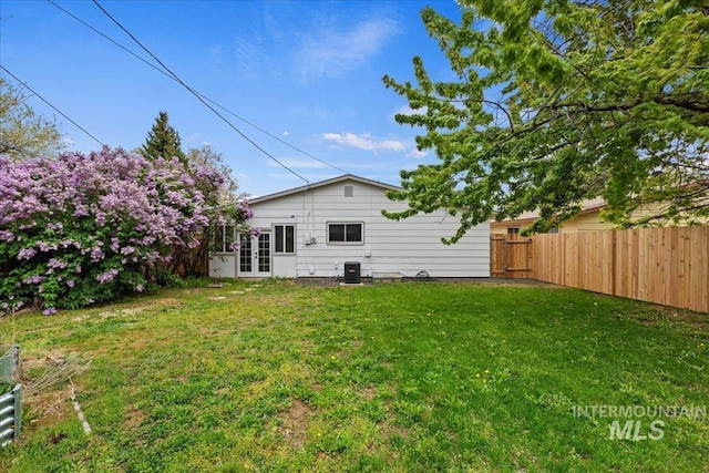 rear view of house featuring a lawn, central air condition unit, fence, and french doors