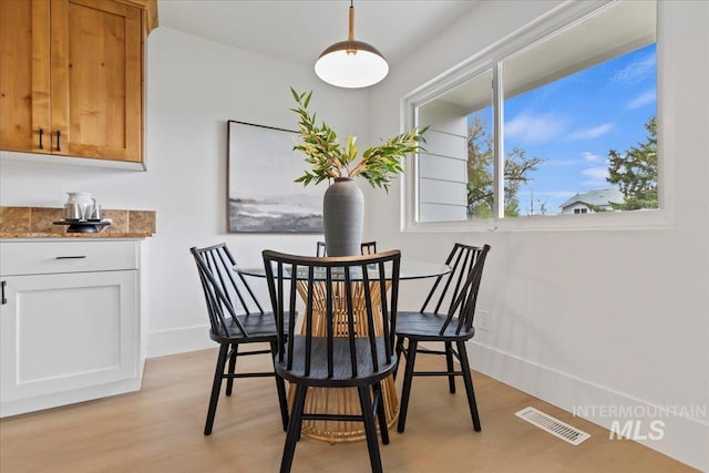 dining space featuring baseboards, visible vents, and light wood finished floors
