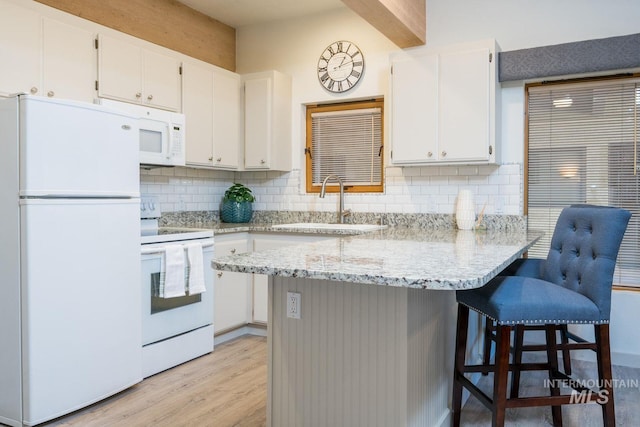 351 S 2nd Ave Unit 602, Ketchum, ID 83340 - kitchen with white appliances, white cabinets, light wood finished floors, decorative backsplash, and a peninsula