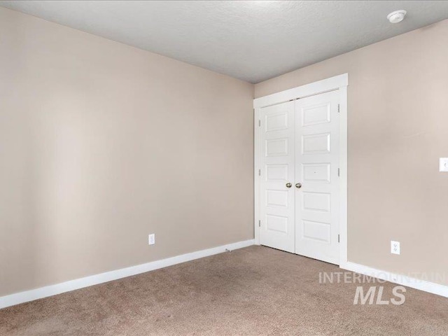 unfurnished bedroom featuring carpet, baseboards, a closet, and a textured ceiling