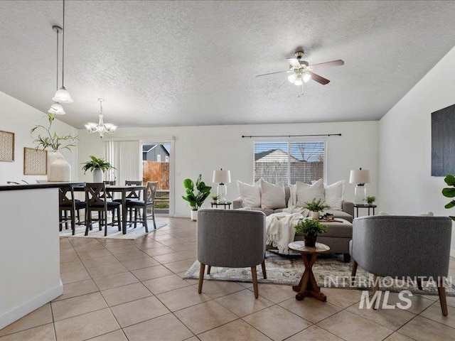 living room featuring plenty of natural light, a textured ceiling, light tile patterned flooring, and ceiling fan with notable chandelier