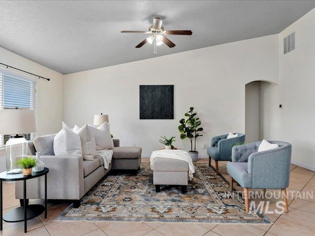 living room with visible vents, lofted ceiling, light tile patterned flooring, arched walkways, and ceiling fan