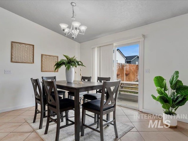 dining space featuring light tile patterned floors, baseboards, a textured ceiling, and a chandelier