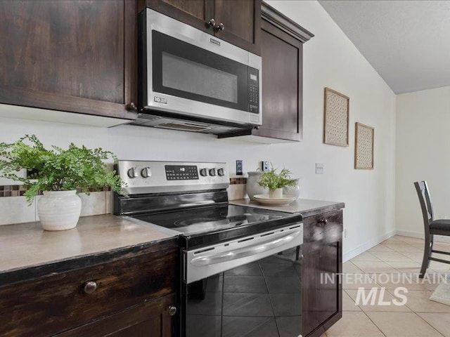 kitchen with light tile patterned flooring, dark brown cabinetry, stainless steel appliances, and baseboards